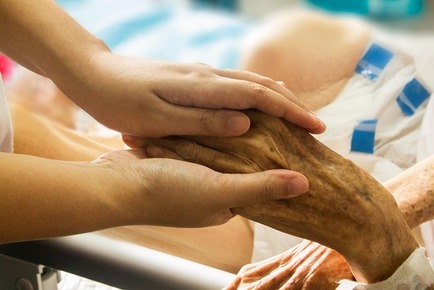 Healthcare provider holding elderly patient's hand