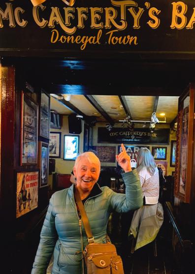  Maureen Weissenrieder, smiling, poses beneath a sign for McCafferty&#039;s Bar in Donegal Town 
