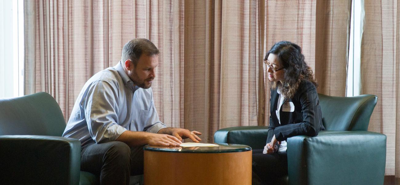 A business professional talks with a business student during a career fair