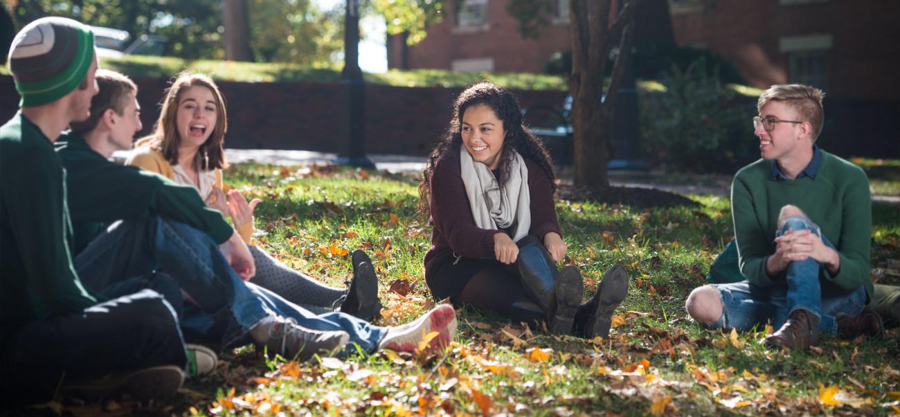 Students laugh and sit in a circle on College Green