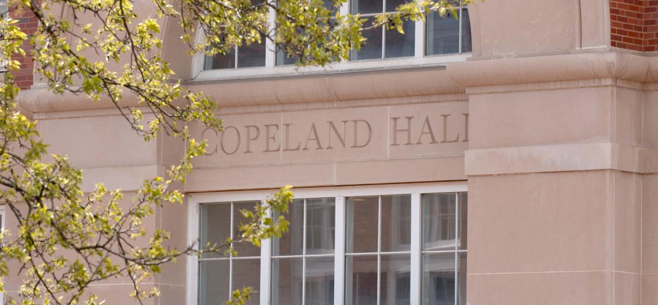 Pink stone building with white windows and "Copeland Hall" outlined on stone wall