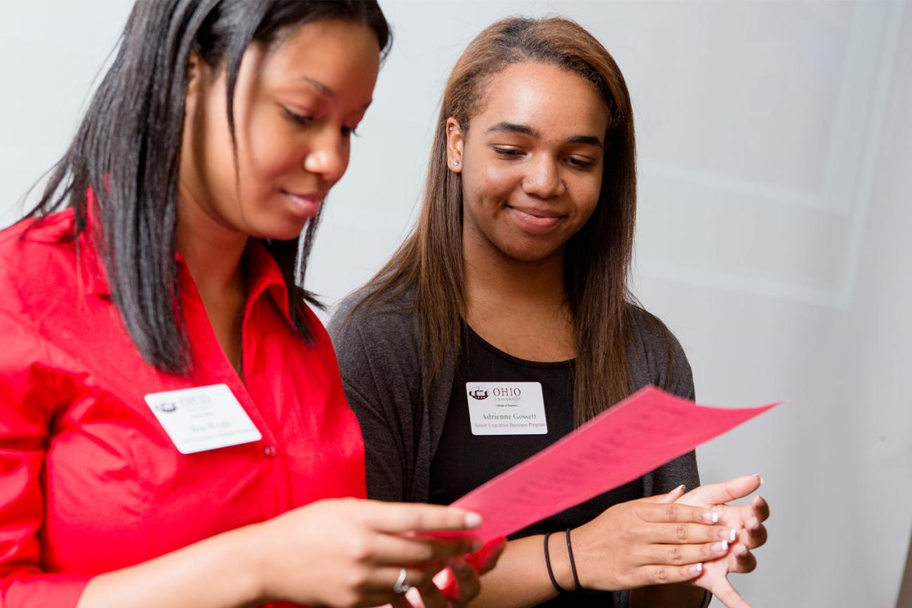 Two women looking down at red paper held in front of them