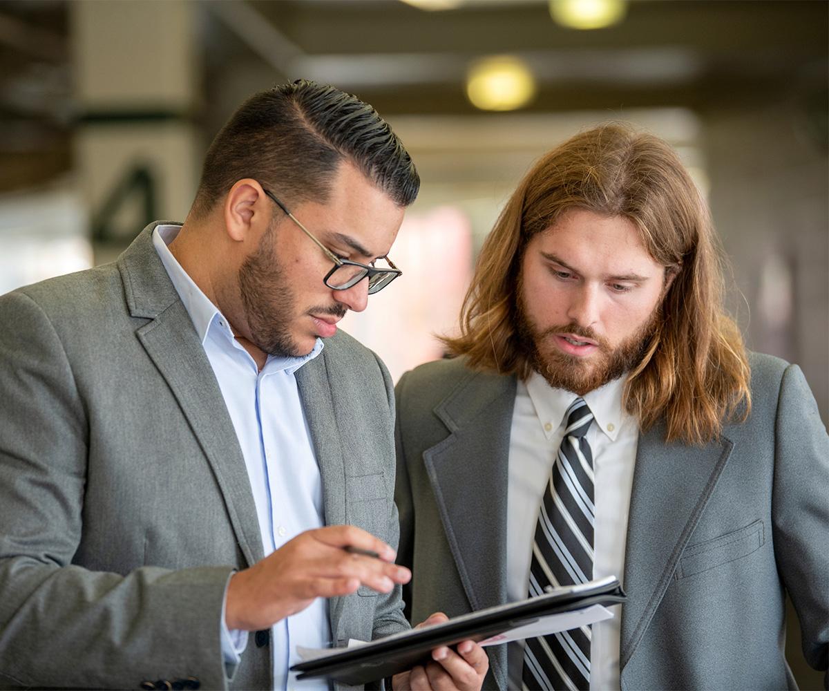 Two people look at an iPad while discussing what they are reading.