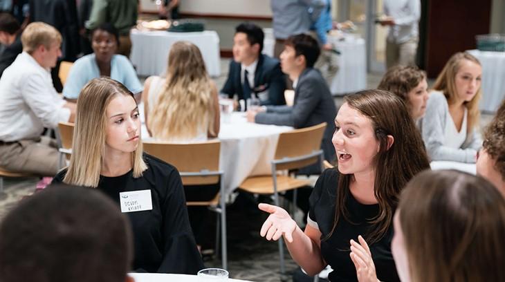 Students in they Schey Sales Centre talk at a conference table