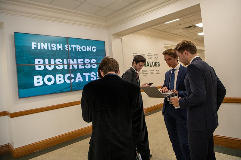 Business students try to problem-solve in a hallway during a Business Cluster team meeting
