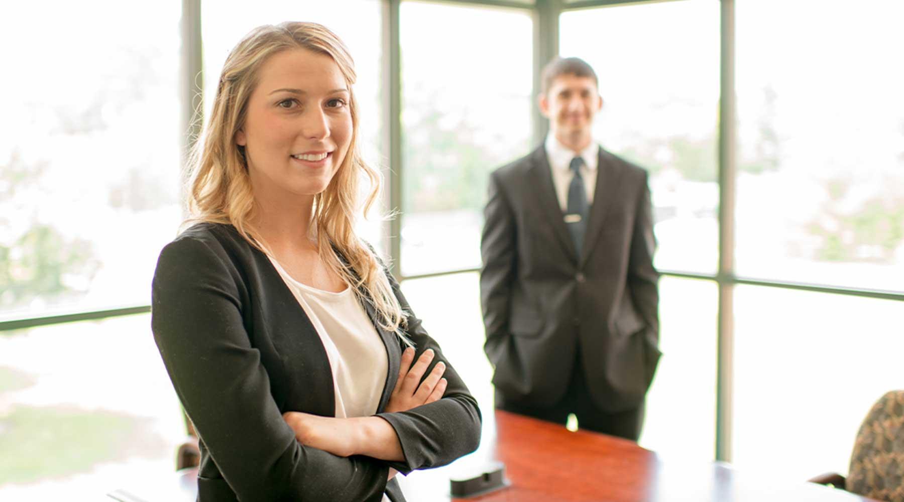A male student and a female student in professional attire standing in a conference room