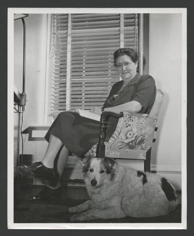 Irma Voigt, Ohio University dean of women, looks up from book while her dog Lady lies beside her, circa 1947