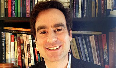 Jonathan Agensky's profile picture Jonathan Agensky, portrait in front of bookshelves