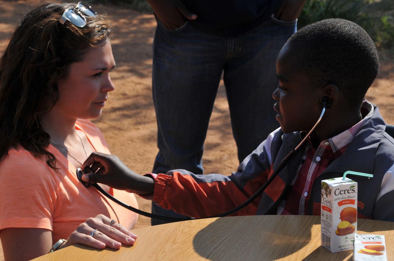 young child uses stethoscope to hear adult woman's heartbeat