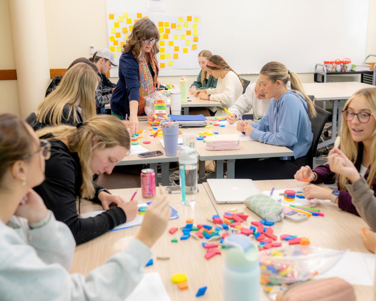 teacher overseeing students using shapes in a math class setting
