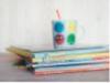 A stack of books and a drink sit on a table