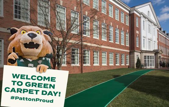 Front of Patton Hall with Rufus holding a "Welcome to Green Carpet Day" sign