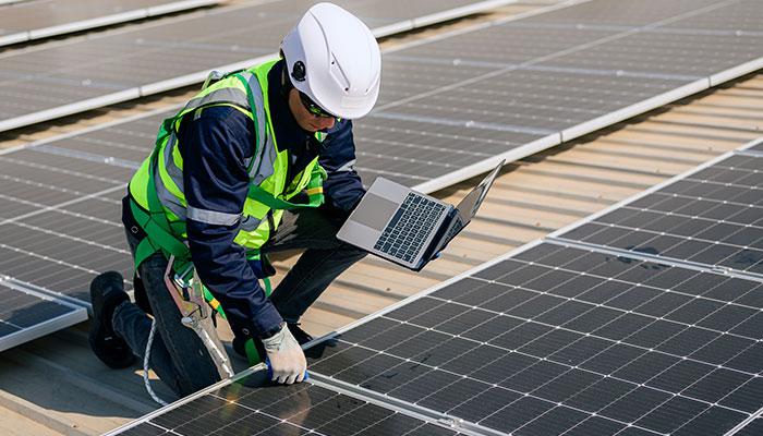 Civil engineer kneeling beside solar panels
