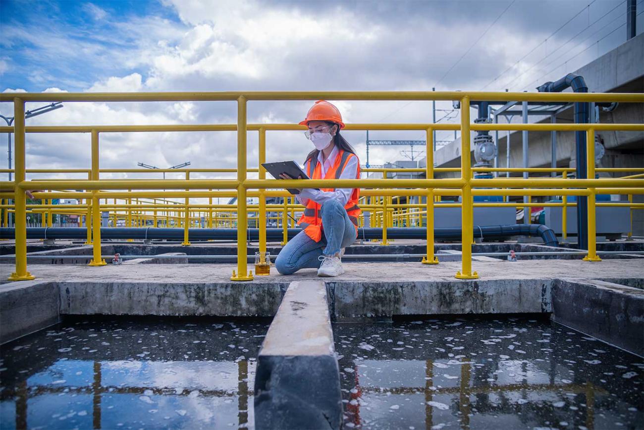 Electrical engineer kneeling by railing holding a clipboard