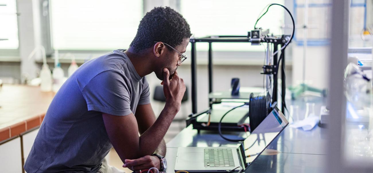 African American male master of an electrical engineering student at the table studying laptop