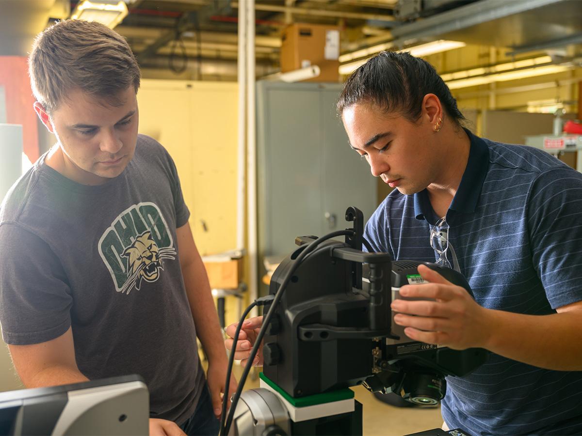 Two students work closely on a task in an engineering lab.