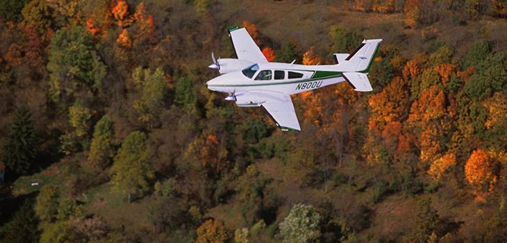 Small plane flying over a forest in autumn