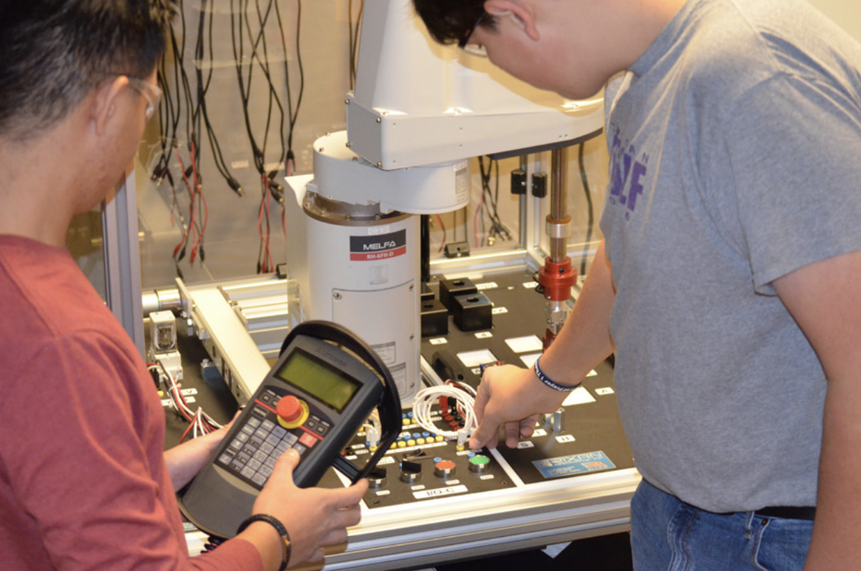 Two students work at control board