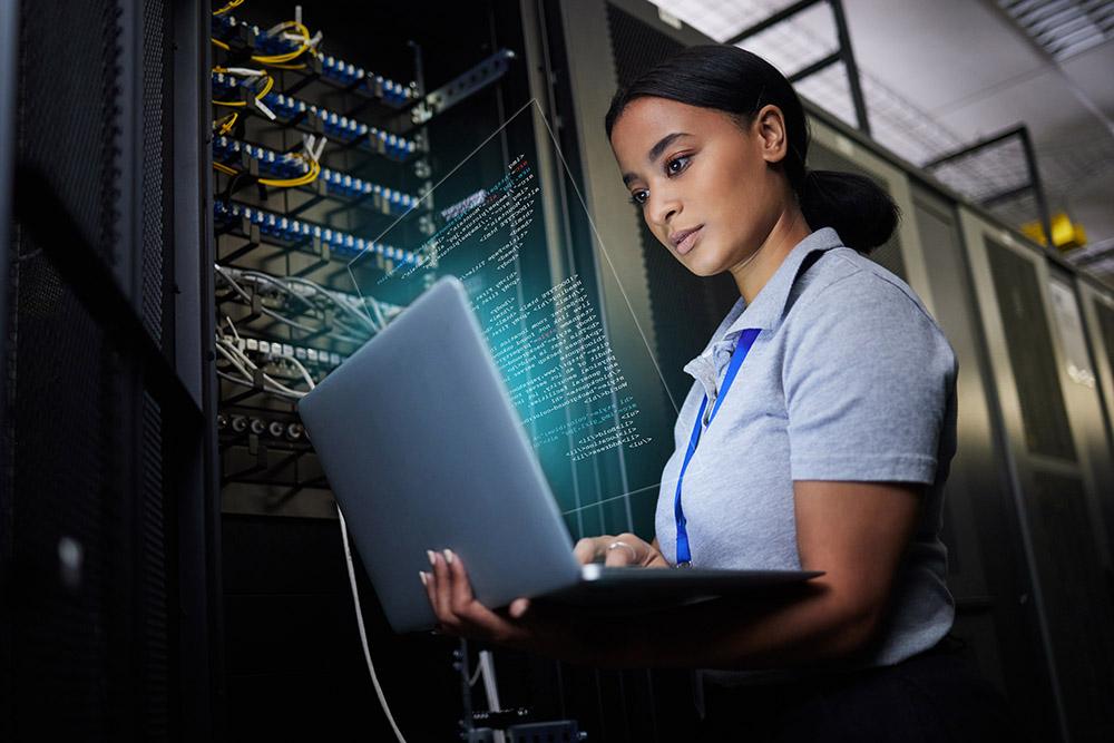 Woman working on a laptop in a server room