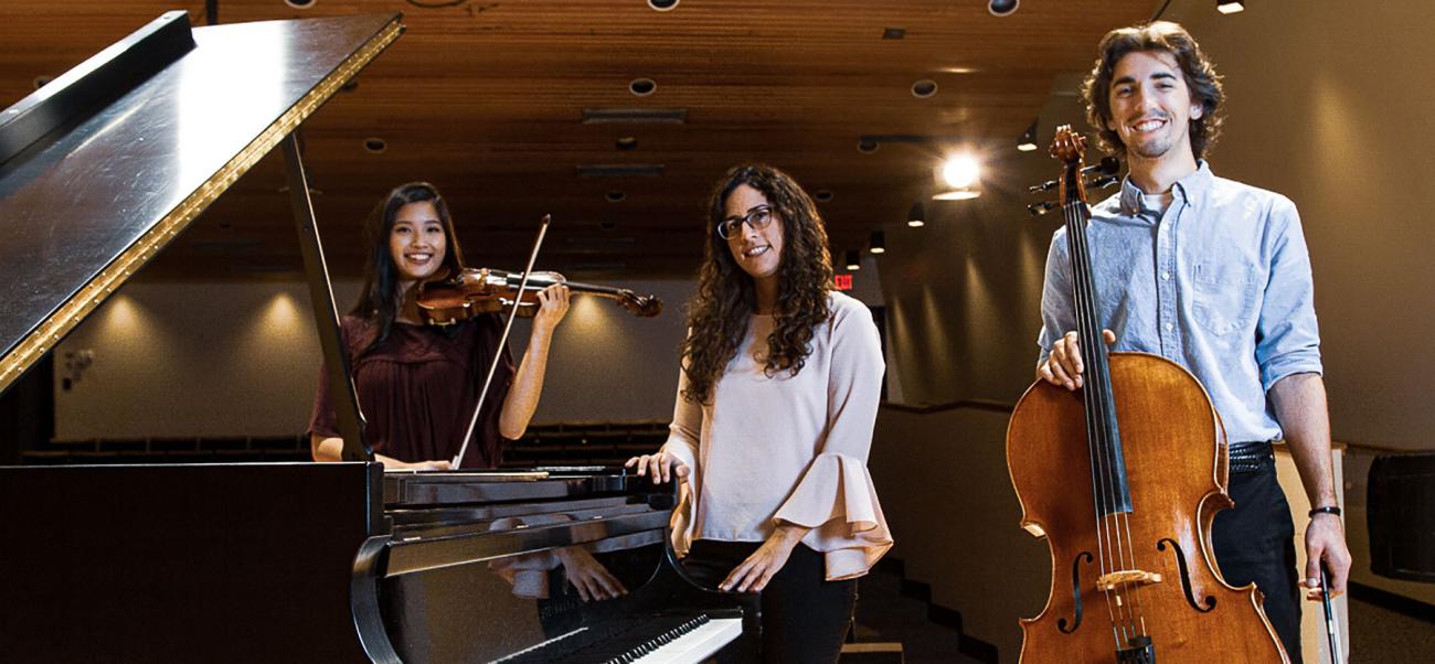 Students pose with different instruments on a stage