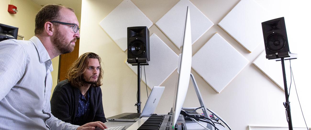 Two people siting at music work station