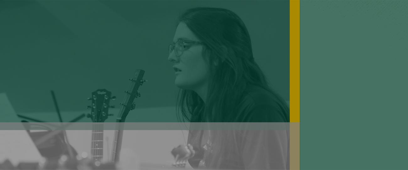 Student sitting with guitars