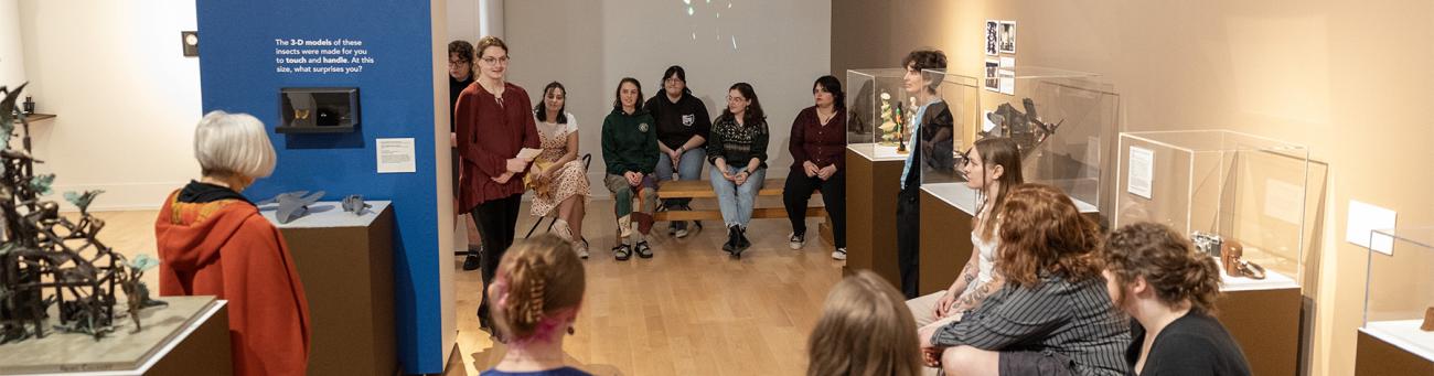 Students gather in a museum space to discuss the exhibits.