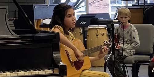 A student plays a guitar at a recital