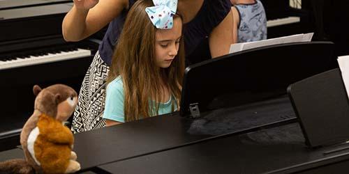 A student in a Piano Safari Friends class with a stuffed chipmunk