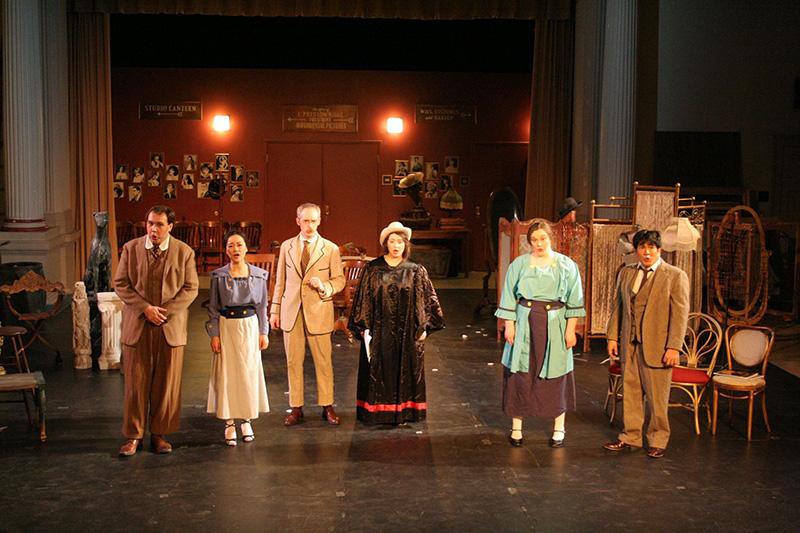 Group of performers in costume on stage. 