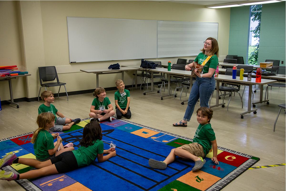 teacher playing guitar to students