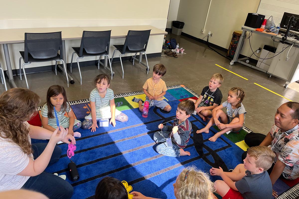 students sitting on rug listening to teacher