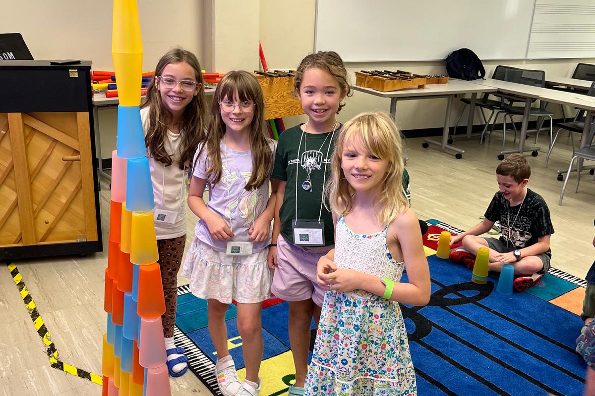 students standing next to stacking sculpture