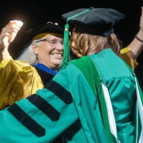 HCOM Graduate hugging Mentor after hooding