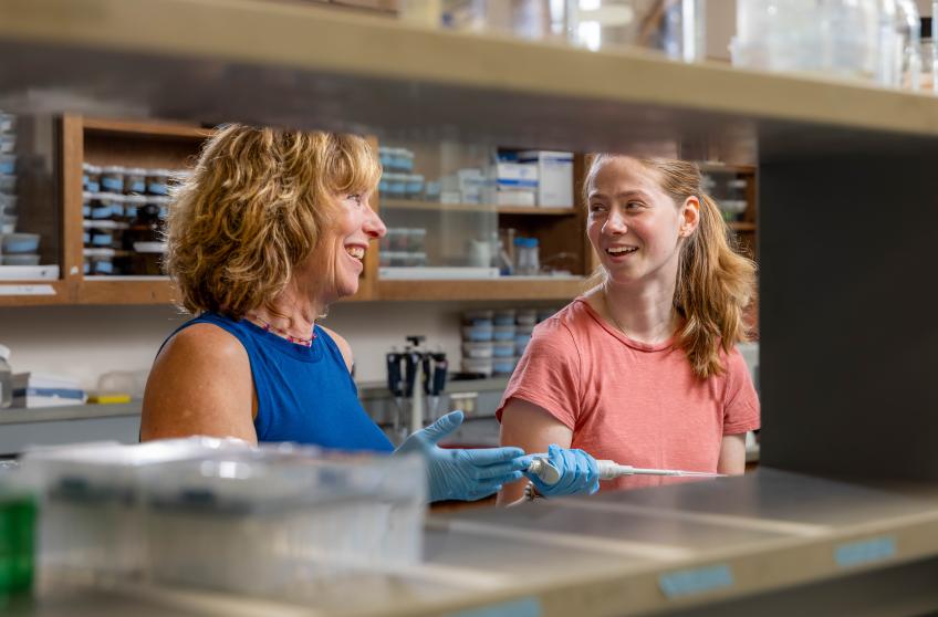 Student working in a laboratory setting with a Professor