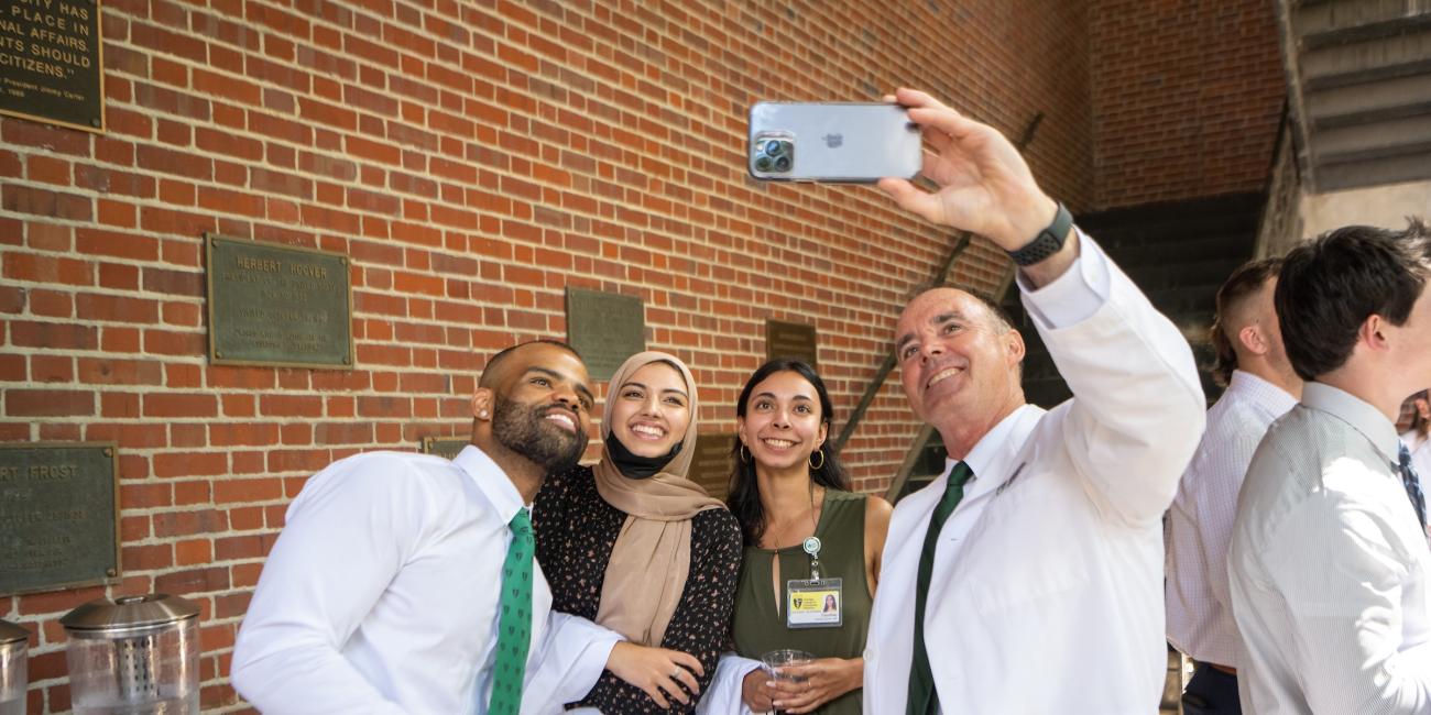 Executive Dean Ken Johnson, DO, takes a selfie with three students during the 2022 White Coat Ceremony
