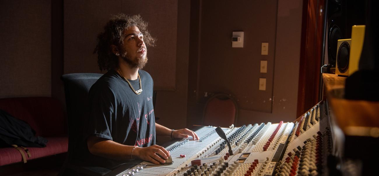 An OHIO student uses a soundboard in a recording studio