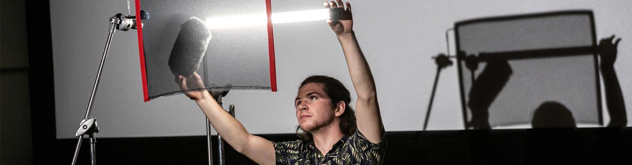 A student holds a light for a film shoot