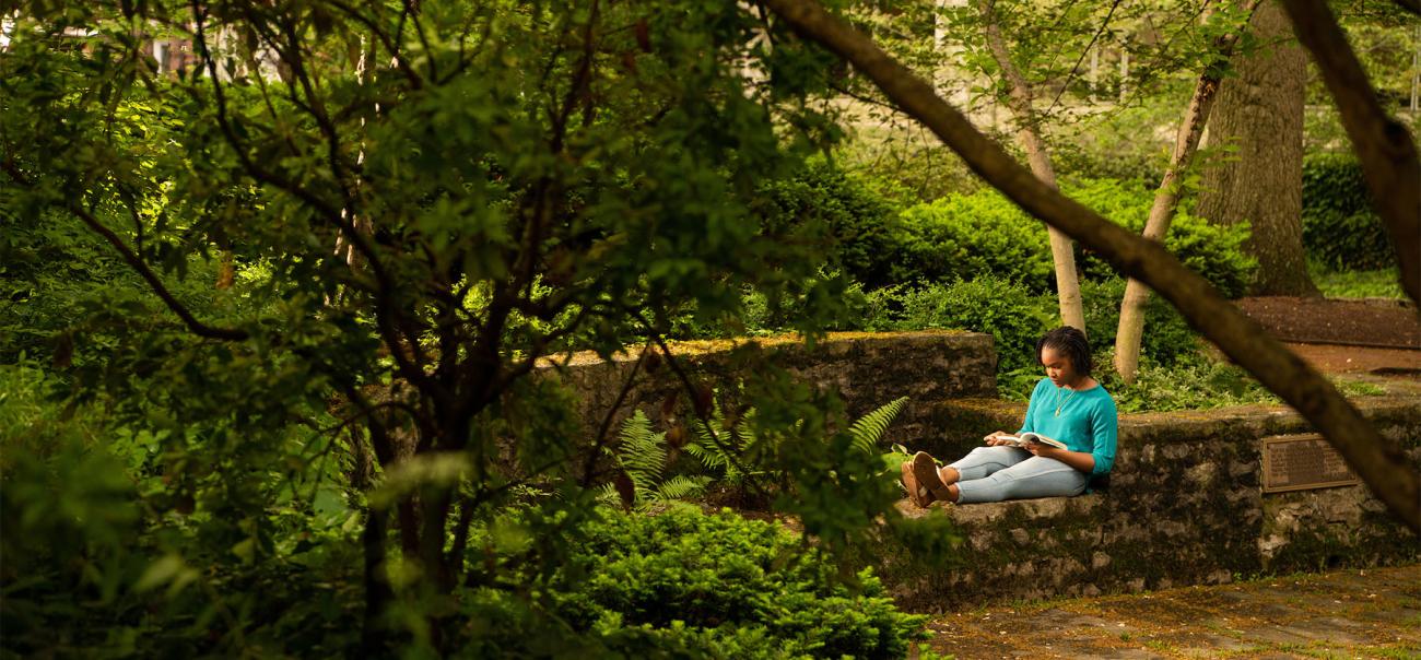 A student sits outside to read near the library.