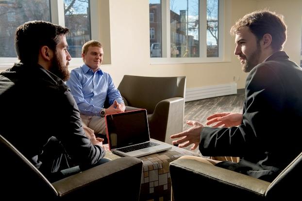 Three ITS students meeting around a table.