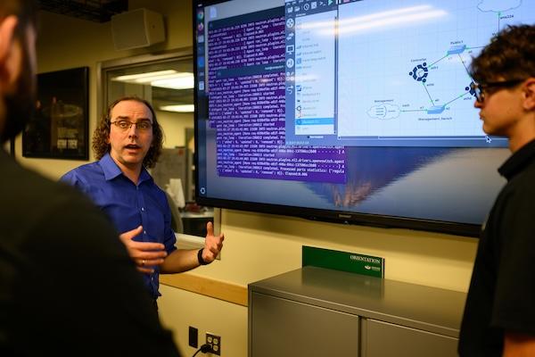Students in advanced networking laboratory discuss a networking configuration lab project