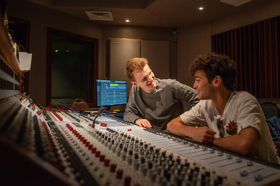 2 high school students working with a sound board