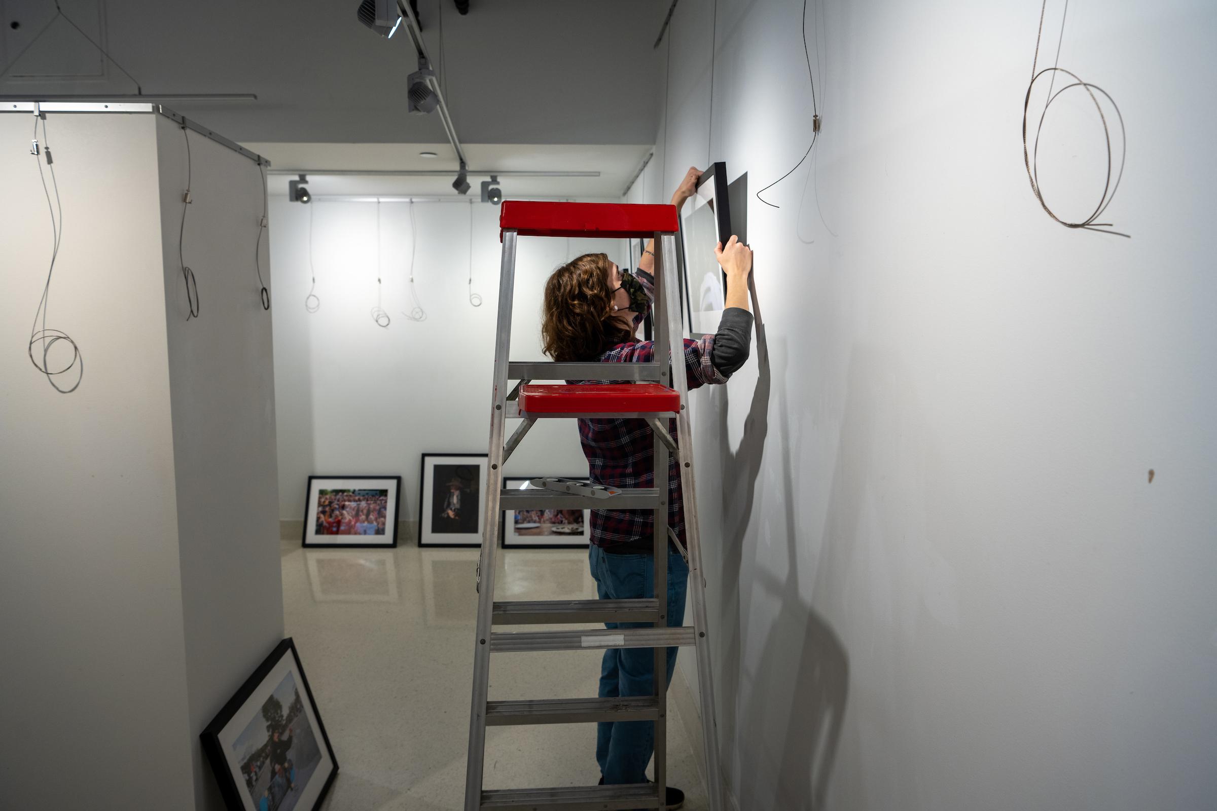 Image of a person putting up art work in the VisCom Focus Gallery.