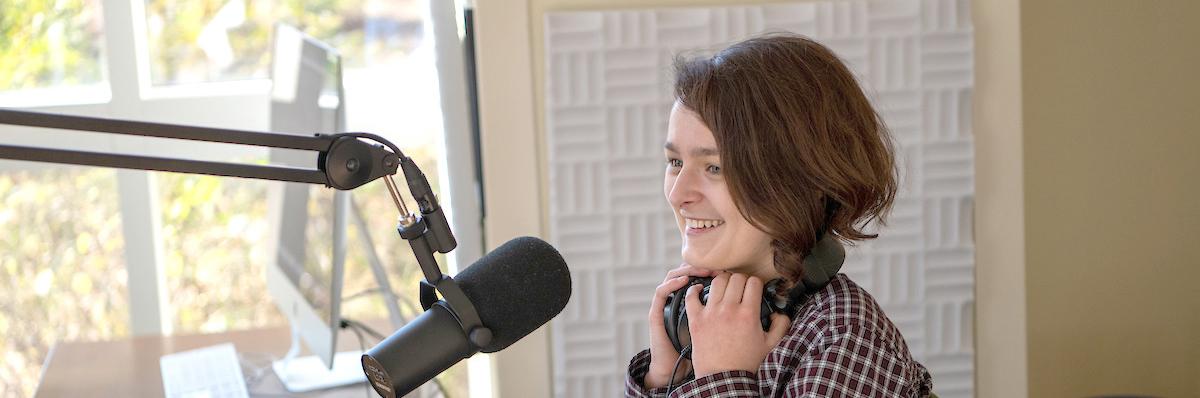 Woman in a podcast studio with a microphone in front of her
