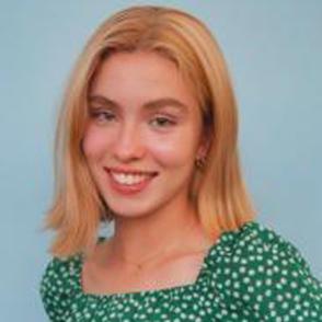 Brigid McSteen smiles, she wears a vibrant green shirt that has white dots on it.