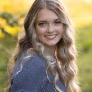 Cassandra Nalazek turned toward the camera, smiling and wearing a blue gray sweater.