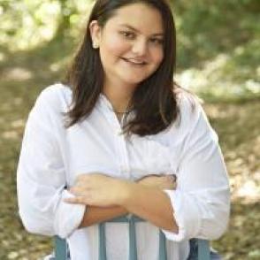 Chloe Fabricante sitting on a blue chair in a white dress shirt.