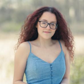 Isabella Curet looks at the camera in a light blue dress, her hands in front of her.