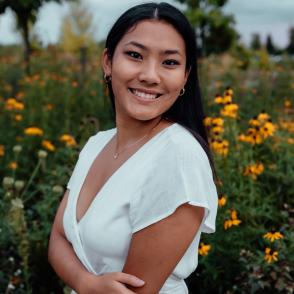 An image of Jessa Chan standing in front of yellow flowers in a white dress.