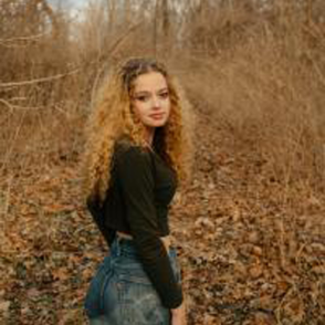 Maeve Fellerhoff looks back at the camera in a black sweater with jeans during Autumn.